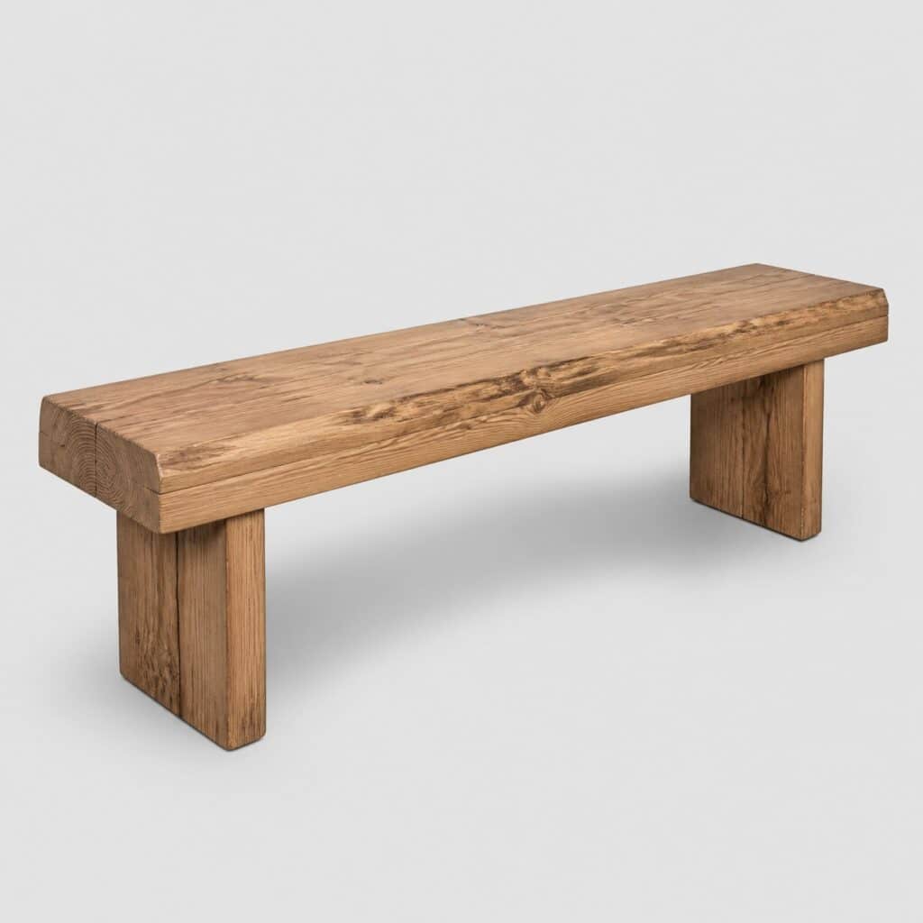 Banc en bois brut massif de forte section photographié sur fond gris clair